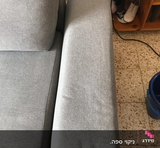 ספה אפורה עם צינור ניקוי כחול על הרצפה